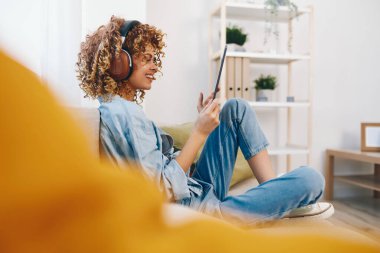 Mutlu Genç Kadın Konforlu Ev Rahatlığı: Tablet 'te Okuma, Oynama ve Sohbet Online, Bir Gülümseme ile Bir Koltuğa Oturmuş,