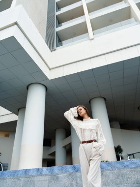 Kıvırcık saçlı şık genç bayan şehirde yaz yürüyüşünün tadını çıkarıyor.