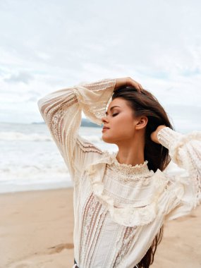 Huzurlu Yaz Güzelliği: Çekici Genç Kadın Gün Batımında Sahilde Keyifli, Okyanus Esintisinin Özgürlüğünü Hissediyor