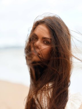 Kaygısız genç kadın sahilde tatilin tadını çıkarıyor, gülümsüyor.