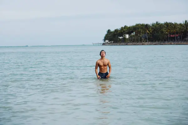 Swimming Man Enjoying Tropical Bliss: Blue Ocean, Sunny Beach, and Joyful Friends