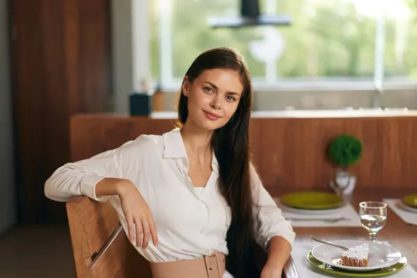Smiling Woman Enjoying Romantic Dinner at Home Beautiful brunette woman sitting at a stylish dining table, smiling ecstatically while indulging in a delicious homemade meal The elegant dining room is