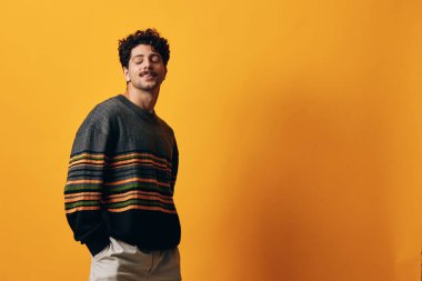 Doğal erkek stili çekici turuncu mutlu poz modern kış moda öğrencisi süveter modaya uygun saç teli gülüşü ciddi bir arka plan.