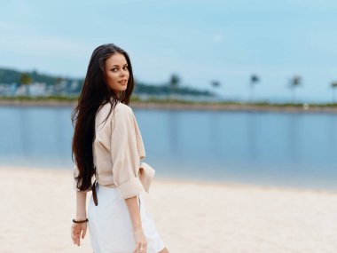 Şık, zarif bayan kumsalda güneşli bir yaz gününün tadını çıkarıyor, Mavi Gök 'ün altında mutlu ve özgür hissediyorum.