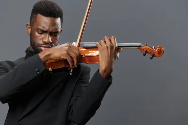身着黑色西服 背景灰暗的黑人男子在雅致的音乐表演中演奏小提琴 — 图库照片
