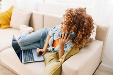 Gülümseyen kadın rahat modern oturma odasında dizüstü bilgisayarda çalışıyor.