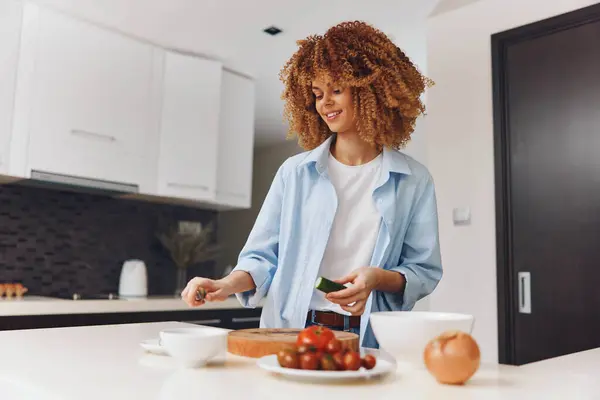 stock image Young African American woman cooking healthy meal in modern kitchen at home, preparing fresh ingredients for dinner