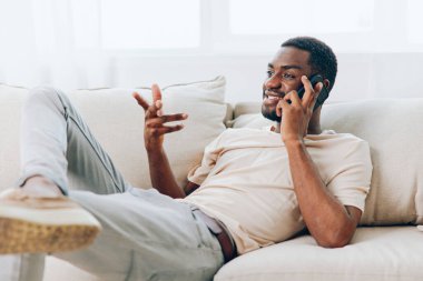 Mutlu Afrikalı Amerikalı Cep Telefonu ile Konuşan Ev 'de Siyah Koltukta otururken ve Akıllı Telefon Modern Yaşam Tarzı ve Teknoloji Konseptine Mesaj Yazarken