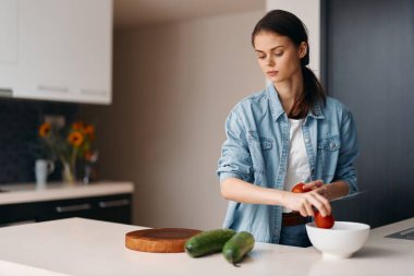 Güzel bir beyaz kadın, becerikli bir aşçı, Mutfağında Taze sebzeler ve beyaz mutfak gereçleriyle sağlıklı salata hazırlıyor.