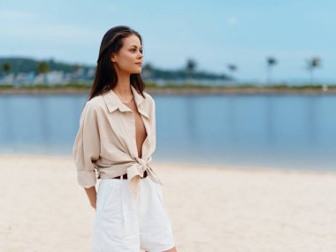 Şık, Çekici Bayan Sahilde Güneşli bir yaz tatilinin tadını çıkartıyor, Muhteşem Mavi Okyanus 'un Arkaplan Olarak Şık ve Rahat Görünüyor