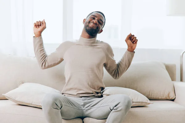 Ein Lächelnder Afroamerikaner Sitzt Auf Dem Sofa Und Genießt Ein lizenzfreie Stockbilder