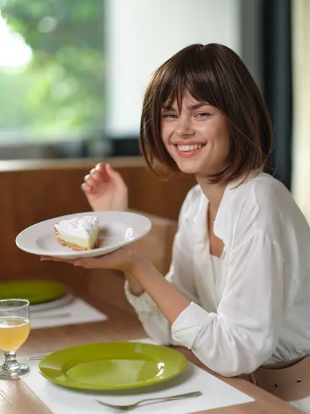 Happy Homemade Dinner Date at an Elegant Dining Table A beautiful young woman with brunette hair sits at a stylishly set dining table, enjoying a romantic homemade meal Her ecstatic smile reflects the