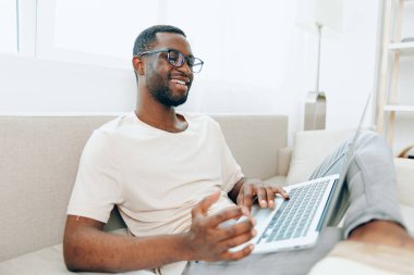 Gülümseyen Afrikalı Amerikalı Modern İçişleri 'nde dizüstü bilgisayarda çalışıyor.