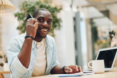 Yaşam tarzı Afrikalı mutlu portre profesyonel erkek iş adamı telefon görüşmesi yetişkin iş adamı ofisi oturan genç bilgisayar siyahi gülümseme teknolojisi