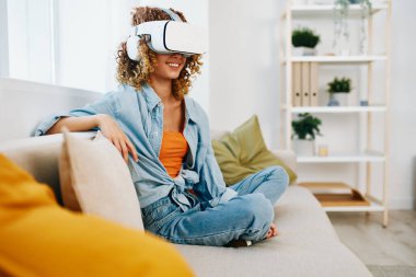 Sanal Gerçeklik Eğlencesi: Gülümseyen Bir Kadın Evde Geleceğin Sanal Gerçekliği Oyunundan Hoşlanıyor, VR gözlüğü takıyor ve Modern Oturma Odasında Bir Koltukta Bir Denetleyici Tutuyor