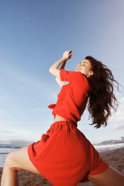 Denizde Dans: Sahilde Kızıl Yaz Moda 'sında Özgürlük ve Eğlenceyi Kucaklayan Neşeli Bir Kadın