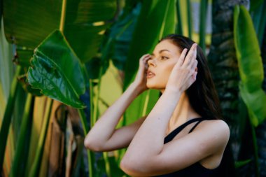 Stresli bir kadın, yeşil bitkinin önünde elleri başının üstünde, sıkıntıda ve hayal kırıklığına uğramış bir şekilde duruyor.