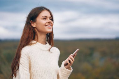 Dağ Kadını: Telefon Bağlantısıyla Doğayı Kucaklamak - Siber alemde Selfie Çeken Gülümseyen Maceracı Bir Gezgin.