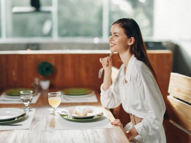 Ev Kadınları 'nda Mutlu Romantik Akşam Yemeği Lezzetli Yemek ve Şarap Odası Bu büyüleyici görüntü, yüzünde neşeli bir ifade olan güzel bir kadını son moda bir restoranda otururken yakalıyor.