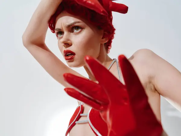 Woman wearing red gloves and red hat with hands on top of head in winter fashion concept photo shoot