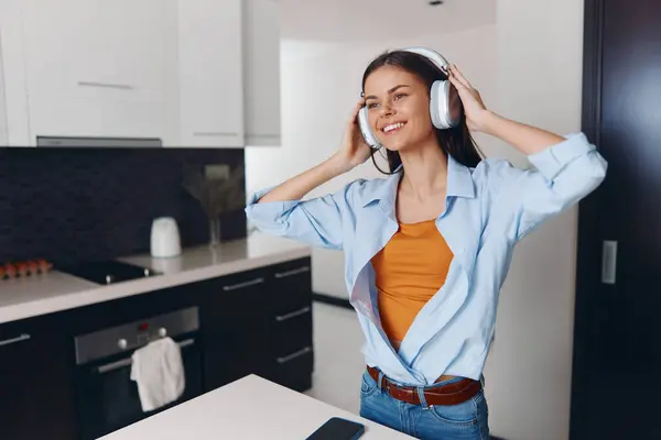 stock image Woman Standing in Kitchen Counter Listening to Music with Headphones On While Enjoying a Moment of Relaxation