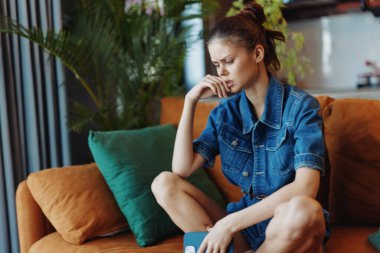 Önünde elleri yüzü ve kitabı olan, koltukta oturan stresli kadın, okumaktan bunalmış.