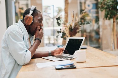 Erkek ofis çalışanı, iş teknolojisi dinleyen, yakışıklı bilgisayarcı, müzik tarzı, genç kulaklıklar kullanarak internet iletişim dizüstü bilgisayarı kullanan bir yetişkin.