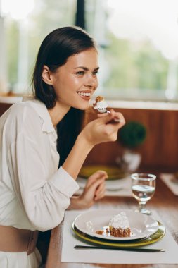 Mutlu Genç Kadın Pasta ve Şarapla Şık Yemek Masasında Romantik Yemeğin keyfini çıkarıyor Güzel esmer bir kadın zarif bir yemek masasında oturuyor, romantik bir yemeğin keyfini çıkarıyor