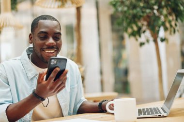Yaşam tarzı adamı, neşeli telefon, internet, gülümseyen genç işadamı, mobil, yetişkin, mesajcı iş adamı, yakışıklı, Afrika teknolojisini erkek akıllı telefonu kullanarak elinde tutmaktan mutluluk duyar.