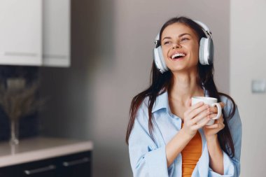 Müzik ve kahve molası veren genç bir kadın, müzik dinlerken elinde bir fincan kahve tutuyor.