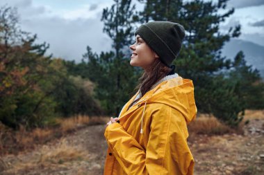 Doğanın Huzurlu Güzelliğini Keşfeden Sarı Yağmurluklu Bir Kadın Orman Yolundaki Mesafeyi Düşünüyor