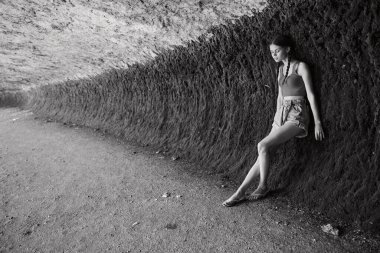 Siyah beyaz bir duvarın yanında yalnız bir kadın oturuyor, tefekkür ve yalnızlık, içgözlem sanatı.