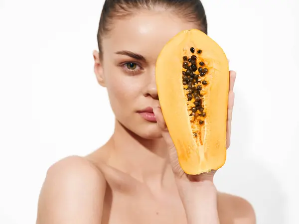 stock image Woman holding a papaya in front of her face with her eyes closed on white background in studio