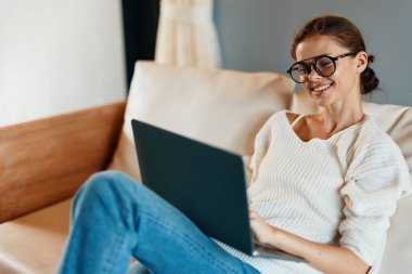 Modern ev ofisinin konforundan faydalanan çekici bir kadın. Etrafı rahat bir atmosferle çevrili ve güzel bir gülümsemesi olan özgür bir kadın.