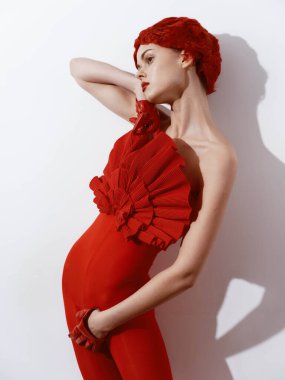 Tarafsız beyaz bir arkaplana karşı poz veren şık kırmızı elbiseli kendine güvenen bir kadın.