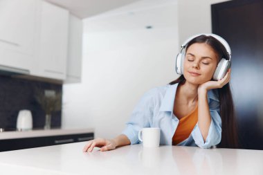 Genç bir kadın, rahat bir kafede müzik dinliyor ve kahve içiyor.