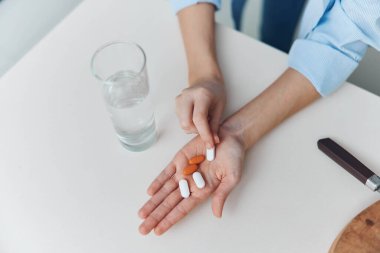 Tıbbi konsept fotoğrafında bıçak ve bir bardak su taşıyan bir kadın.