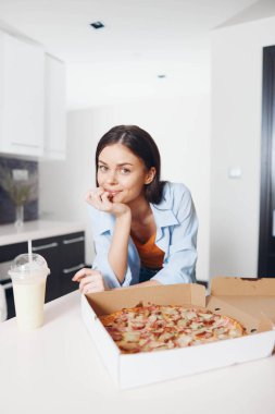 Lezzetli bir pizzanın ve sıcak bir restoranın masasında içkinin tadını çıkaran genç bir kadın.