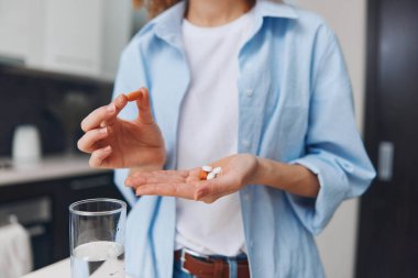 Kadın elinde hapla su bardağının önünde duruyordu. İlaç konsepti, kadın ilacı içiyordu.