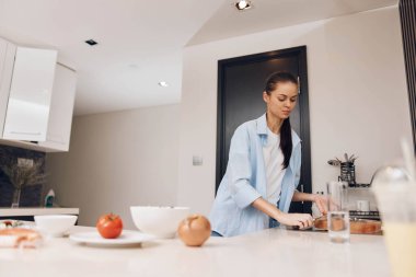 Mutfakta, beyaz tezgahın önünde yemek pişiren bir kadın.