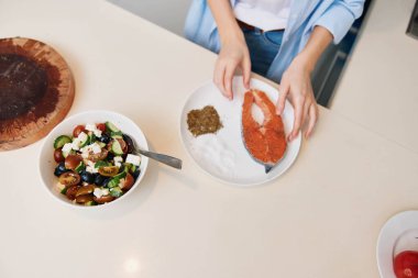 Kadın mutfak tezgahında çeşitli malzemelerle ev yapımı lezzetli yemekler hazırlıyor.