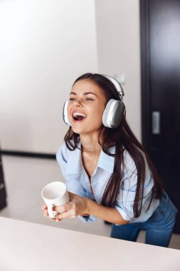 Hoş bir atmosferde Müzik ve Kahveden Hoşlanan Kadın Kulaklıklar ve Önünde Bir Kupa