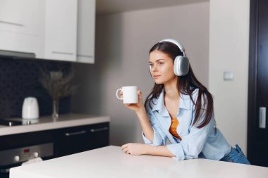 Genç bir kadın, kahve ve müzik eşliğinde masada sessiz bir anın tadını çıkarıyor.