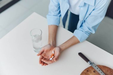 Kadın Tutma Hapı ve Su İlacı Konsepti Kadın eli, Tıbbi Tablet ve İçme Suyu Kapalı