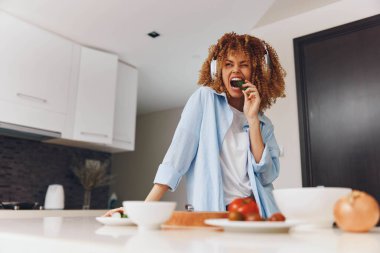 Mutfakta elinde bir fincan kahve ve bir tabak yemek tutan bir kadın, sabah rutini konsepti.