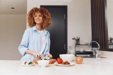 Mutlu Afrikalı Amerikalı kadın mutfağında yemek pişiriyor gülümseyerek lezzetli yemekler hazırlıyor.