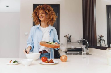 Mutlu Afrikalı Amerikalı kadın evinde taze salata yiyor, sağlıklı yaşam tarzı konsepti.