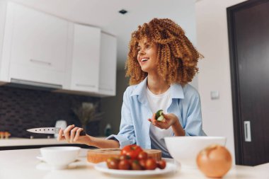 Afro-Amerikan kadın ev mutfağında tutku ve neşeyle lezzetli yemekler pişiriyor.