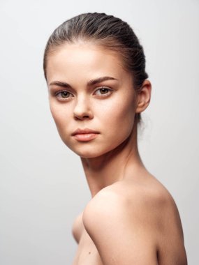 Güzel bir genç kadının portresi, pürüzsüz, pürüzsüz bir ten, kendine güvenen ve ışıl ışıl, beyaz arka planda soyutlanmış.