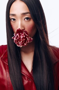 Elinde çiçek tutan kırmızı ceketli bir kadının portresi, doğrudan kameraya bakıyor.